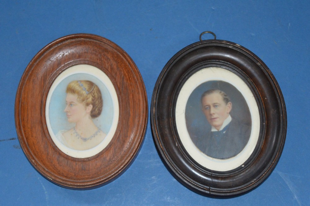 A pair of late 19th-century oval miniature watercolour portraits depicting a woman and a man in matching moulded wooden frames.