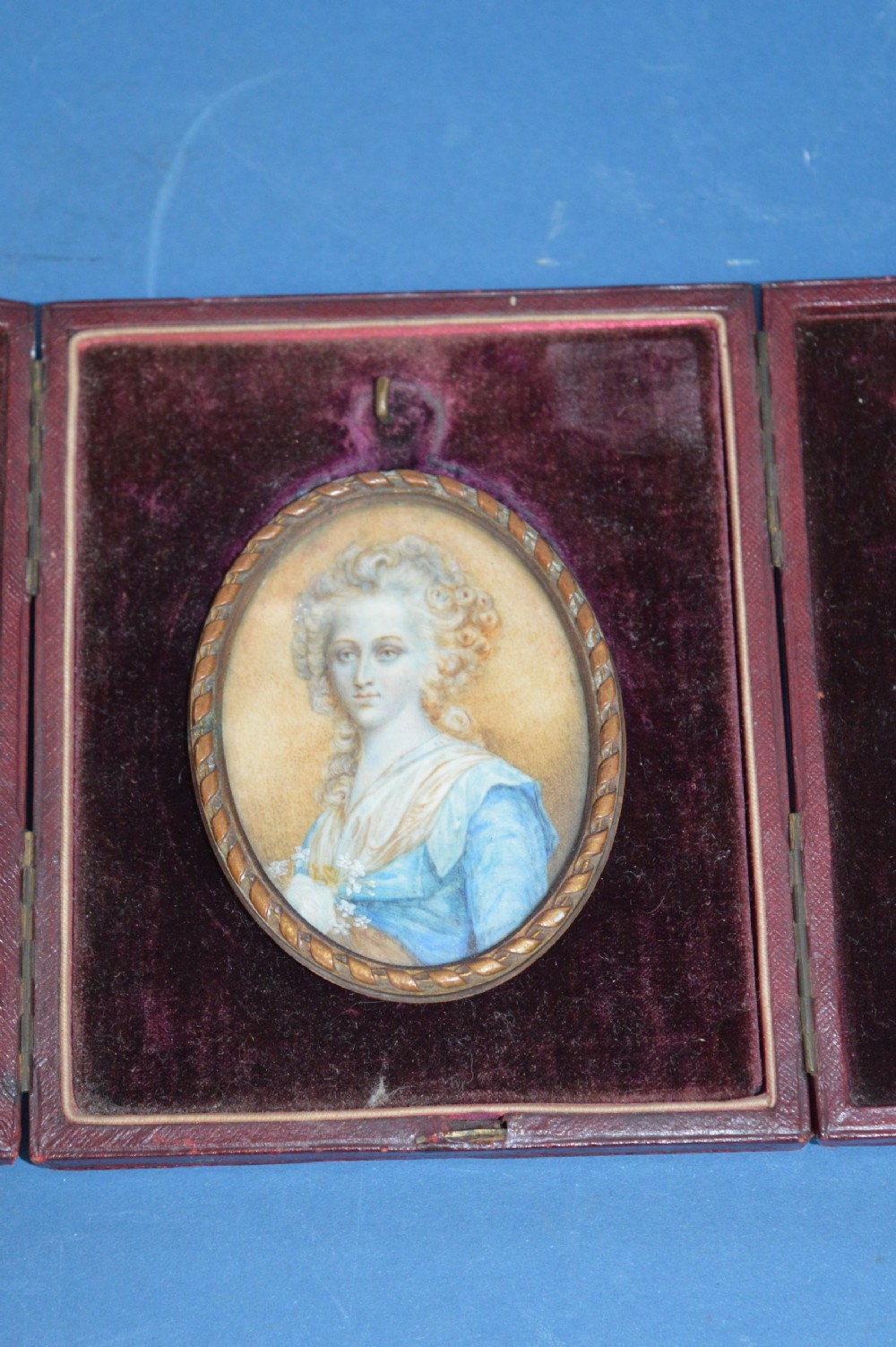 Two Georgian portrait miniatures from circa 1800, one set in a rectangular giltwood frame and the other in a velvet-lined burgundy leather folding case. View II