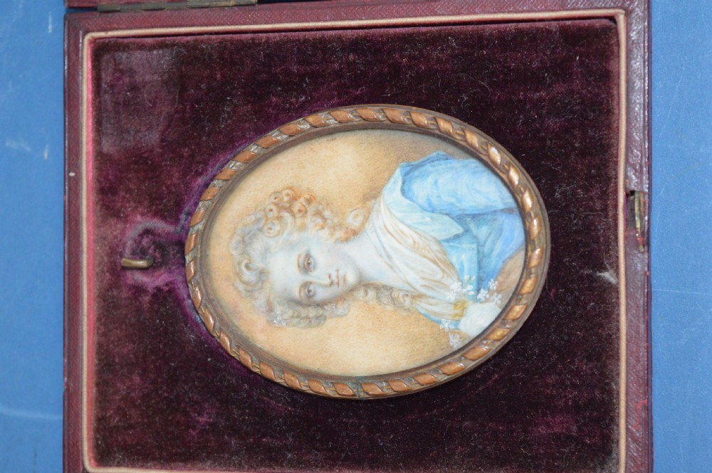 Two Georgian portrait miniatures from circa 1800, one set in a rectangular giltwood frame and the other in a velvet-lined burgundy leather folding case. View IV