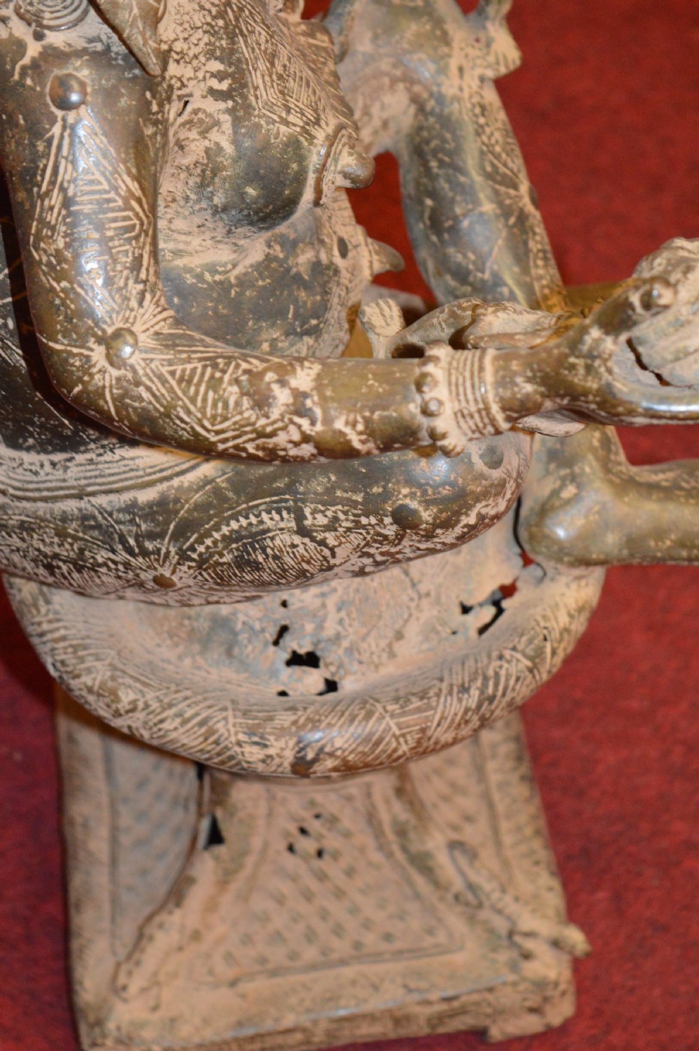 A cast bronze West African maternity statue depicting a seated female figure with elaborate headwear and detailed surface carving holding two smaller child figures. View VII