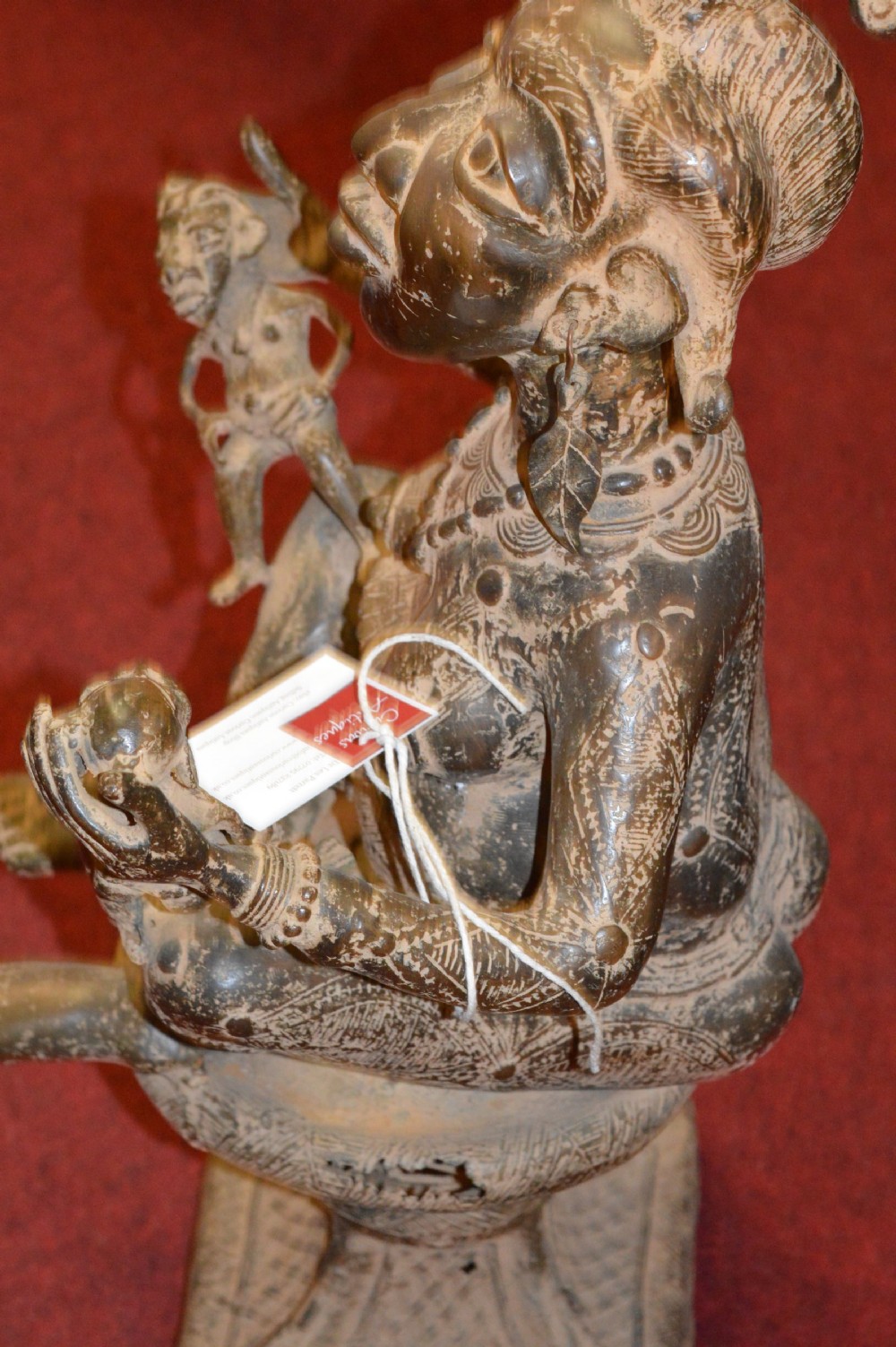 A cast bronze West African maternity statue depicting a seated female figure with elaborate headwear and detailed surface carving holding two smaller child figures. View VIII