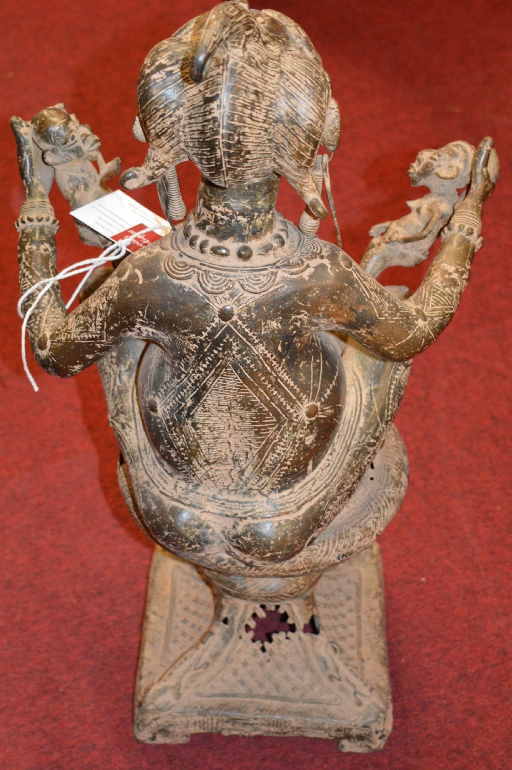 A cast bronze West African maternity statue depicting a seated female figure with elaborate headwear and detailed surface carving holding two smaller child figures. View X