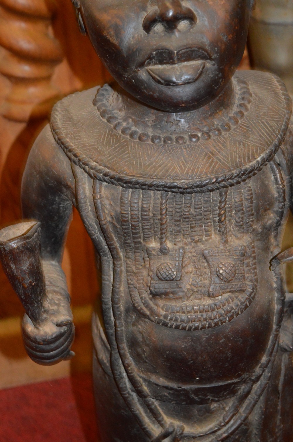 A standing cast bronze West African warrior figure with ceremonial headwear, detailed chest ornamentation, and traditional waist garment. View VI