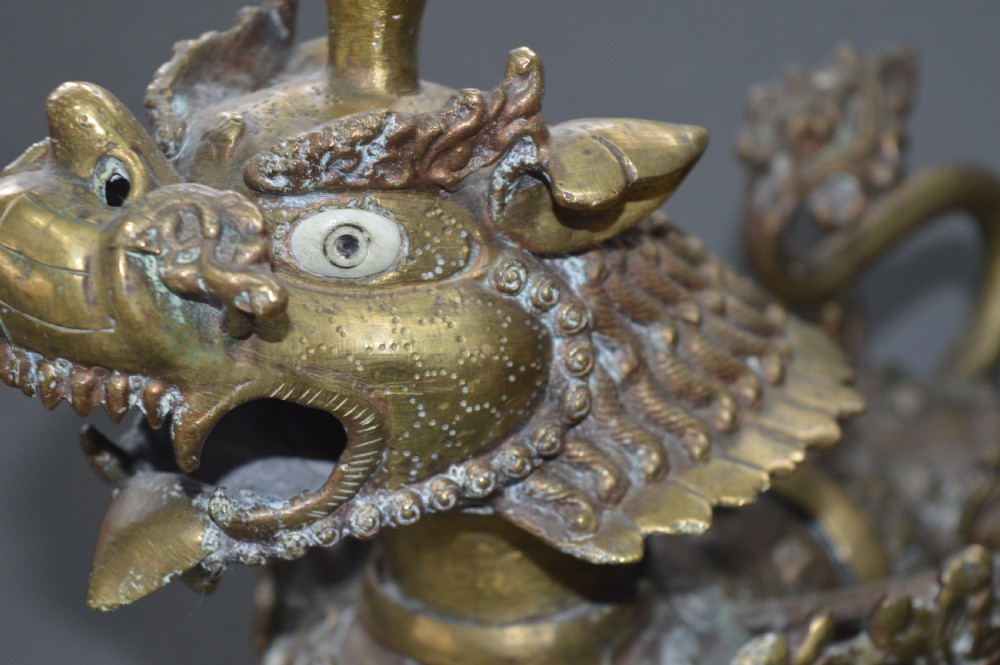 A pair of 19th-century cast bronze Tibetan temple lions featuring stylized wings, open jaws, and original patinated surface. View III
