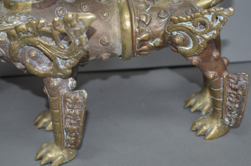 A pair of 19th-century cast bronze Tibetan temple lions featuring stylized wings, open jaws, and original patinated surface. View VI