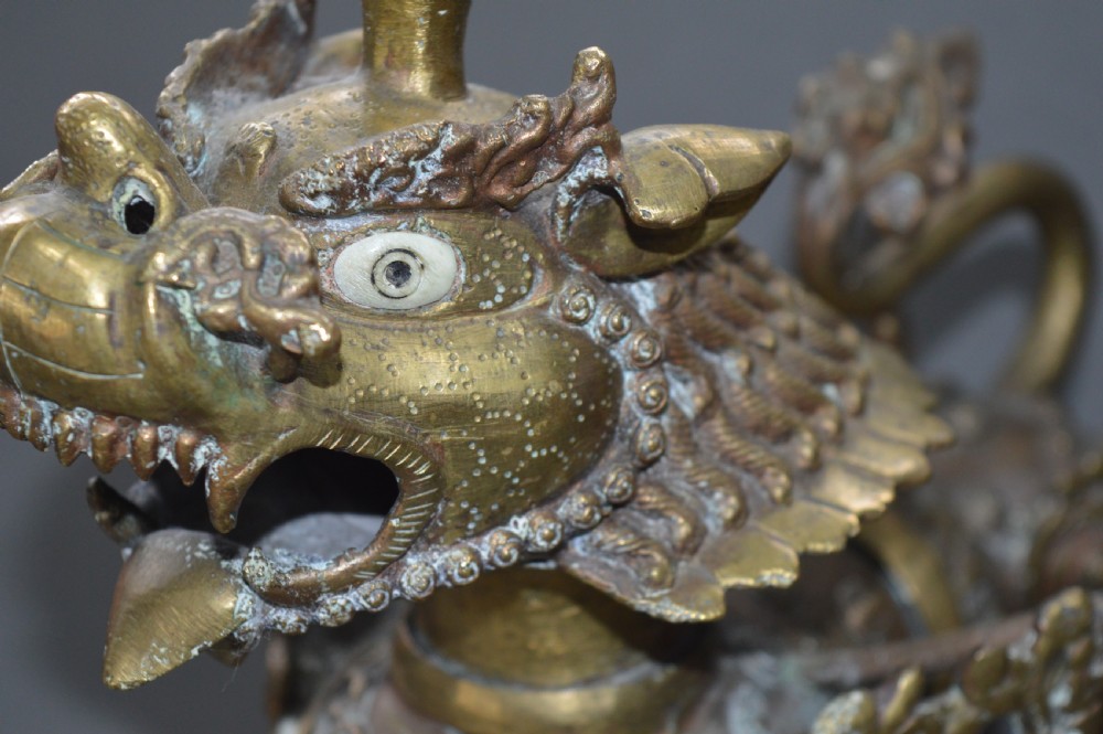 A pair of 19th-century cast bronze Tibetan temple lions featuring stylized wings, open jaws, and original patinated surface. View VII