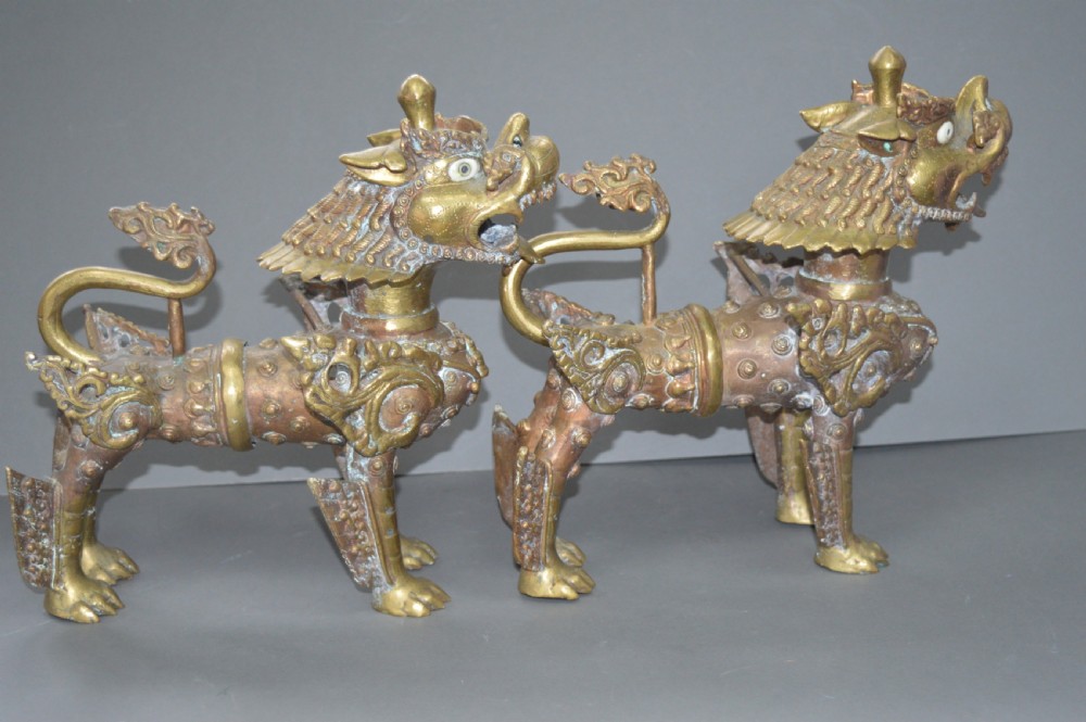A pair of 19th-century cast bronze Tibetan temple lions featuring stylized wings, open jaws, and original patinated surface. View IX