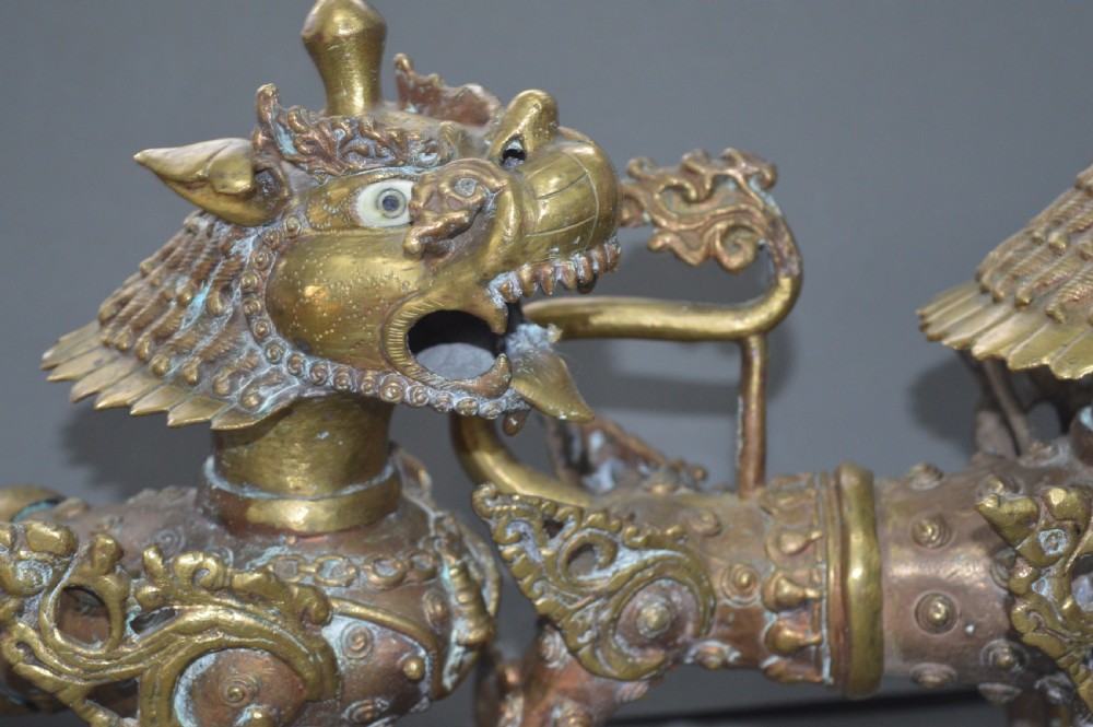 A pair of 19th-century cast bronze Tibetan temple lions featuring stylized wings, open jaws, and original patinated surface. View XII