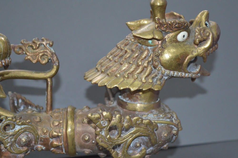 A pair of 19th-century cast bronze Tibetan temple lions featuring stylized wings, open jaws, and original patinated surface. View XIII