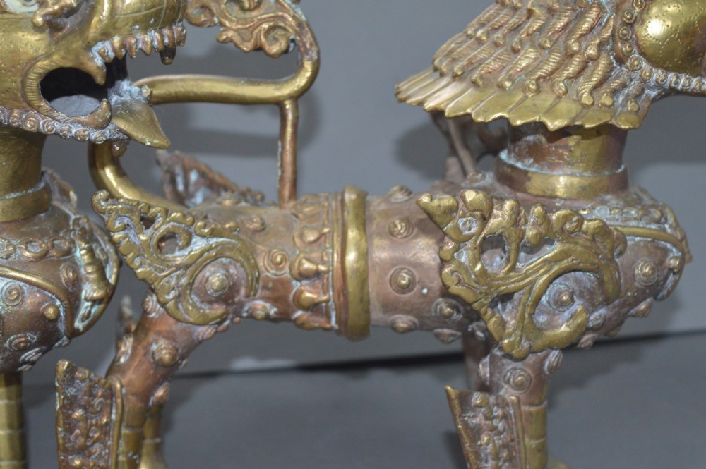 A pair of 19th-century cast bronze Tibetan temple lions featuring stylized wings, open jaws, and original patinated surface. View XIV