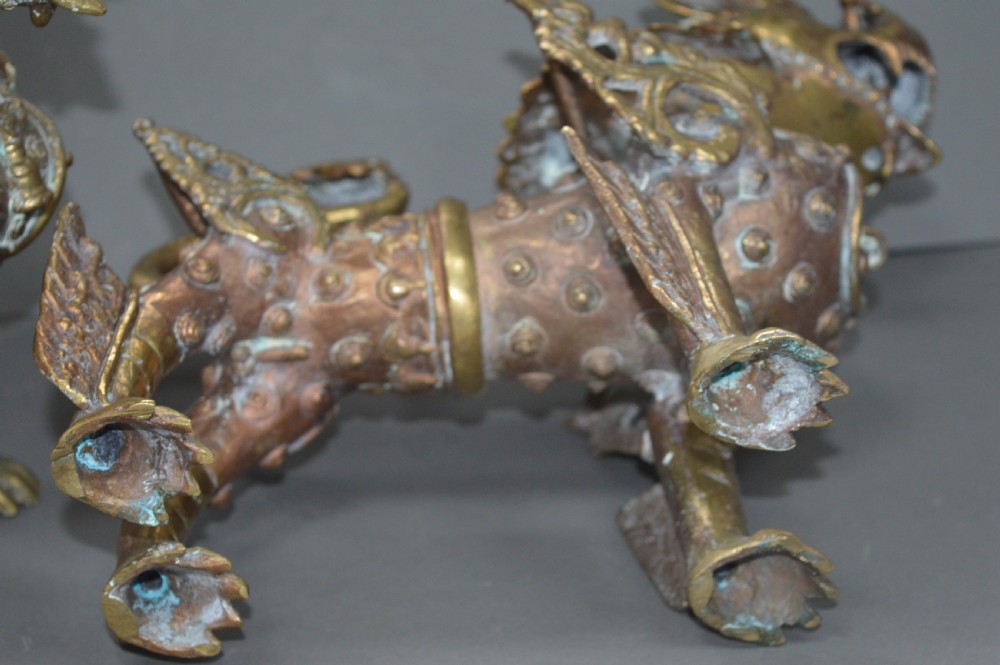 A pair of 19th-century cast bronze Tibetan temple lions featuring stylized wings, open jaws, and original patinated surface. View XV