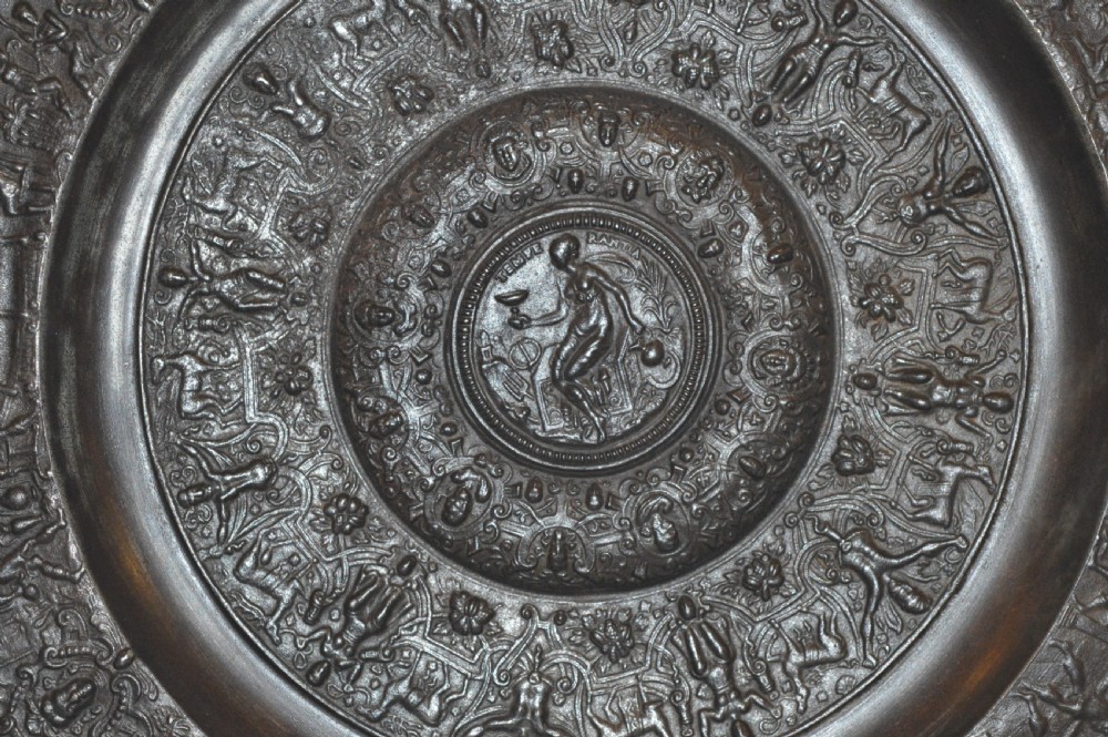 A large circular dark bronze charger featuring concentric bands of classical relief figures surrounding a central classical medallion. View II