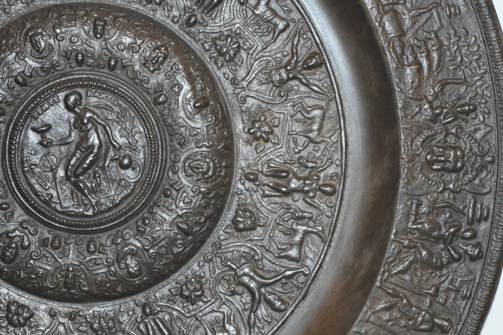 A large circular dark bronze charger featuring concentric bands of classical relief figures surrounding a central classical medallion. View V