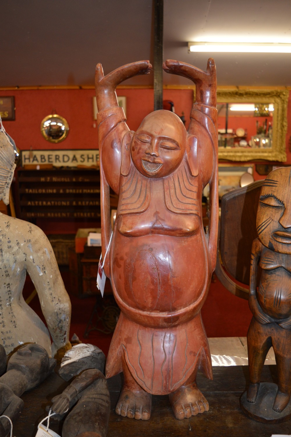 A nineteenth-century carved wooden statue depicting a laughing Buddha figure standing with arms raised above its head.