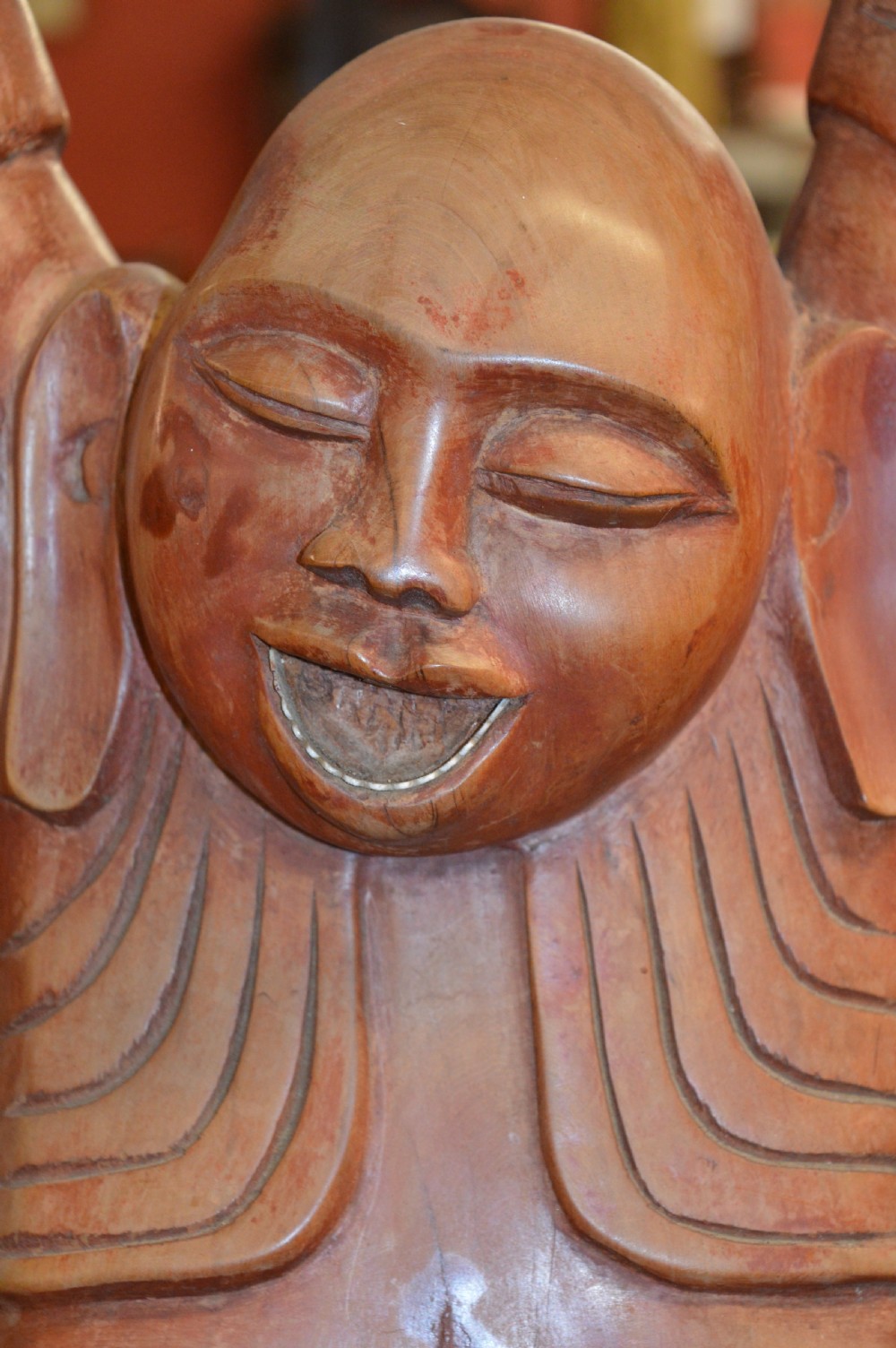 A nineteenth-century carved wooden statue depicting a laughing Buddha figure standing with arms raised above its head. View V