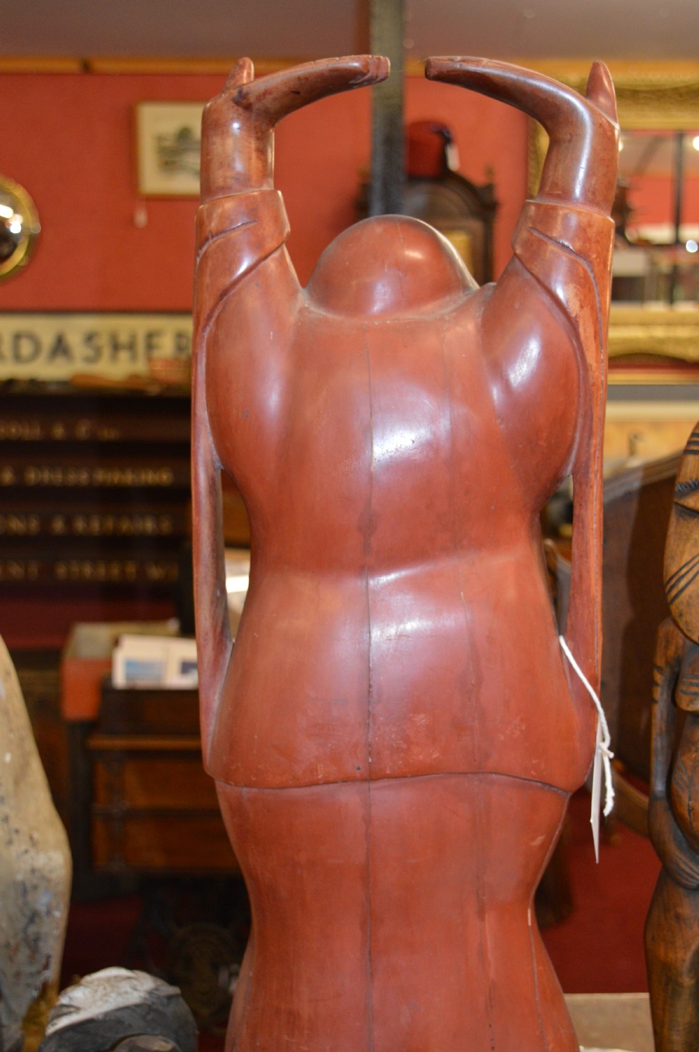 A nineteenth-century carved wooden statue depicting a laughing Buddha figure standing with arms raised above its head. View X