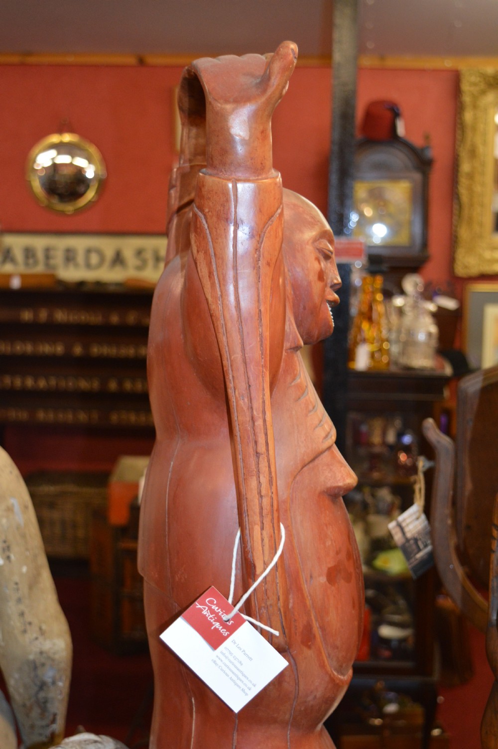 A nineteenth-century carved wooden statue depicting a laughing Buddha figure standing with arms raised above its head. View XII