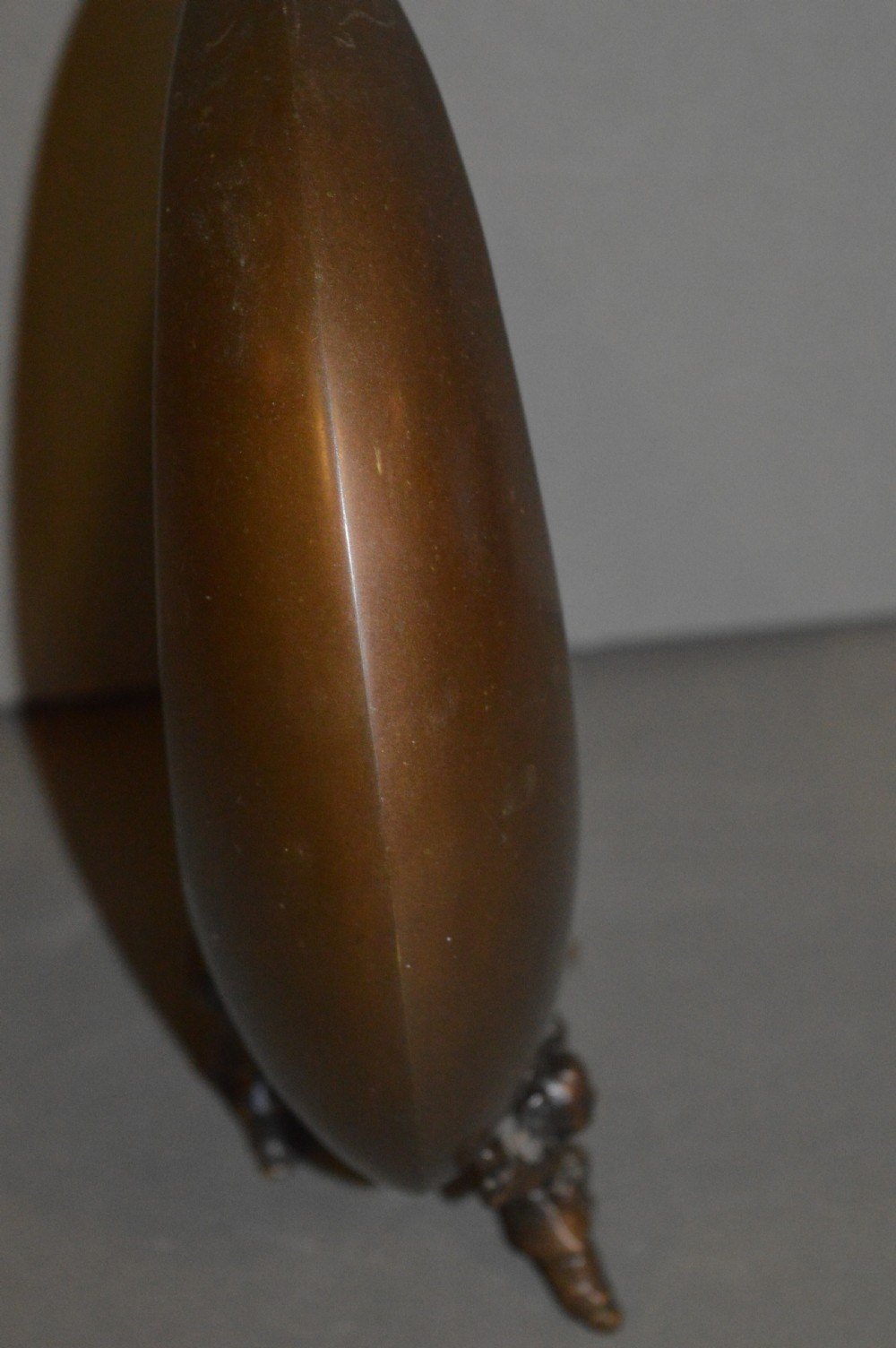 A bronze incense burner crafted in a crescent moon shape with figural supports and a central removable grate. View IV