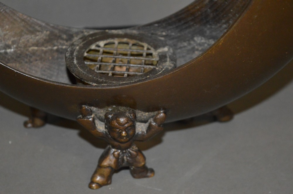A bronze incense burner crafted in a crescent moon shape with figural supports and a central removable grate. View VI