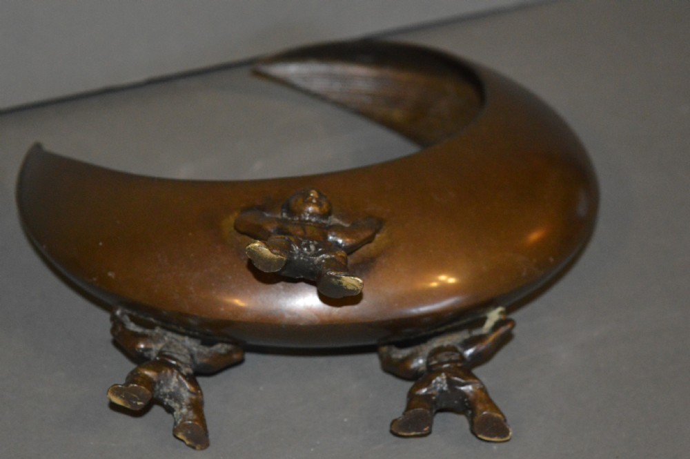 A bronze incense burner crafted in a crescent moon shape with figural supports and a central removable grate. View VII