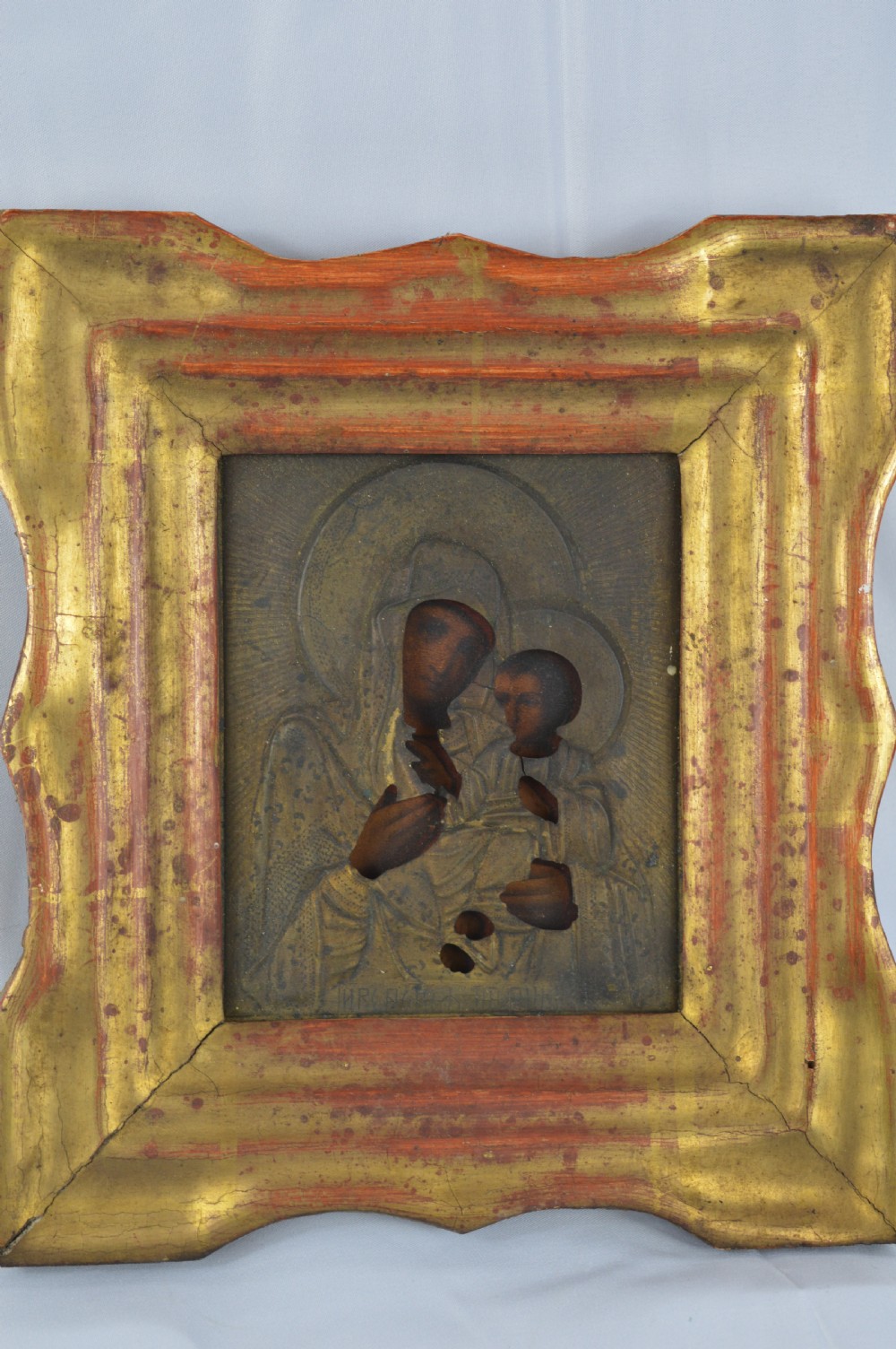 An early 20th-century Russian Orthodox icon depicting the Virgin Mary and Christ Child inside a carved, gilded wooden frame.