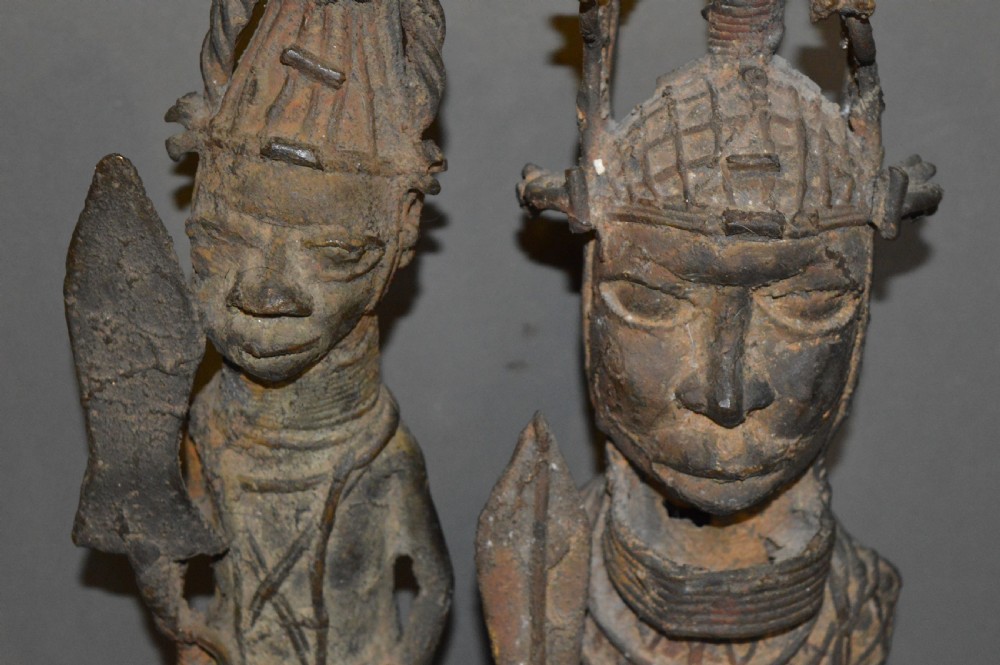 A pair of cast bronze West African warrior statues featuring textured headpieces, patterned garments, and held spears. View IV
