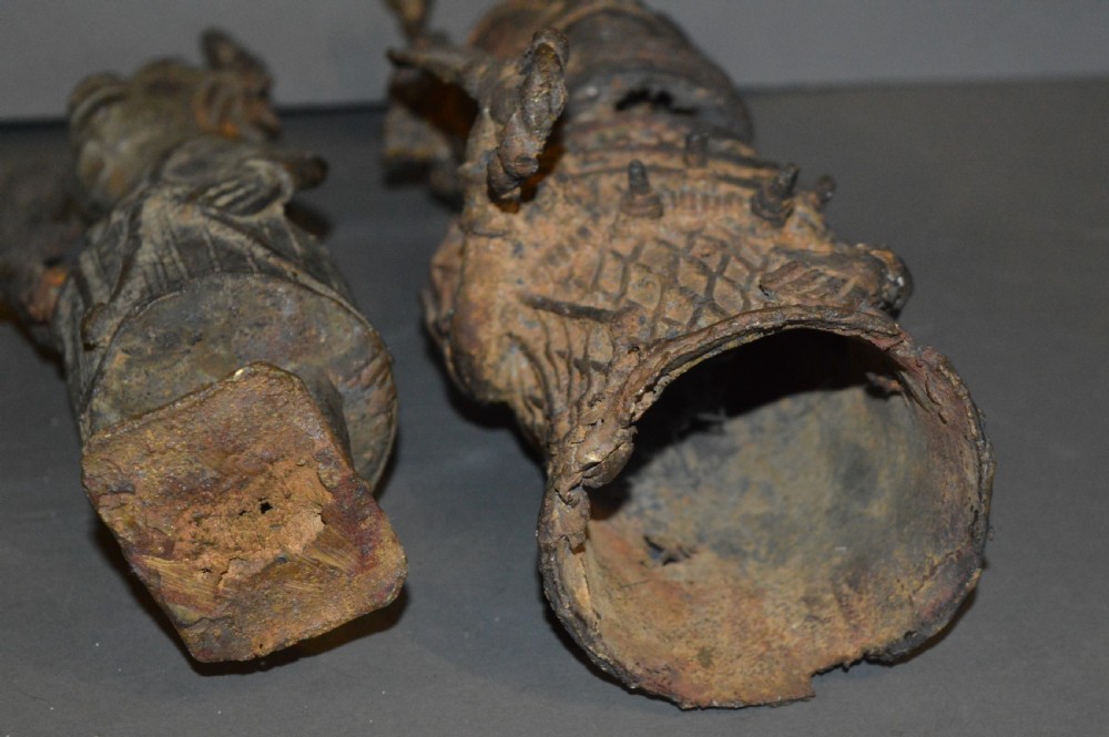 A pair of cast bronze West African warrior statues featuring textured headpieces, patterned garments, and held spears. View IX