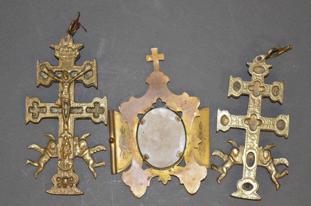 A set of three late nineteenth-century Spanish brass devotional items, including two Caravaca double-barred crosses with angel figures and one central hinged miniature shrine. View II