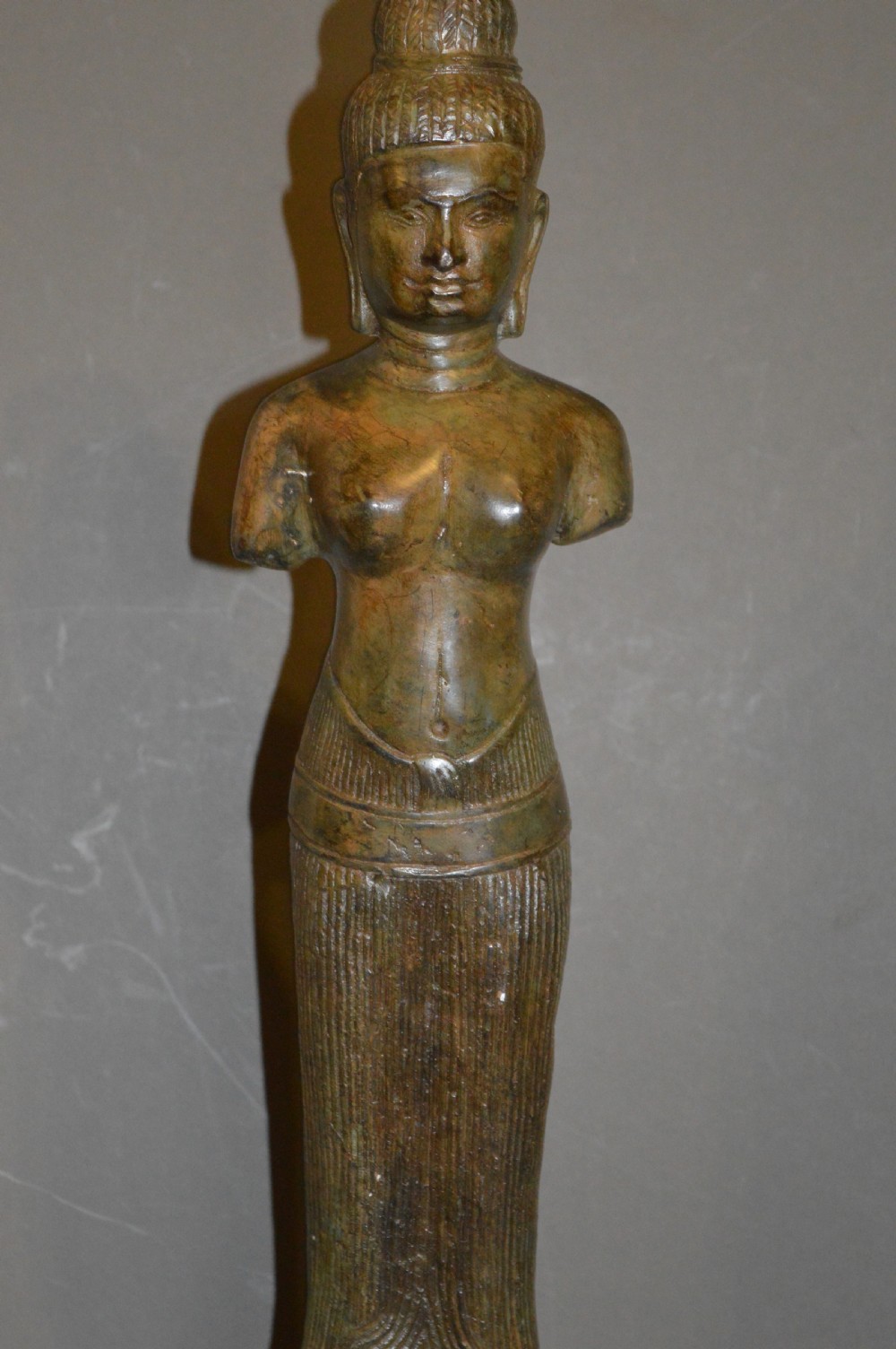 A standing patinated bronze figure of a Buddhist deity mounted on a turned wooden socle base. View II