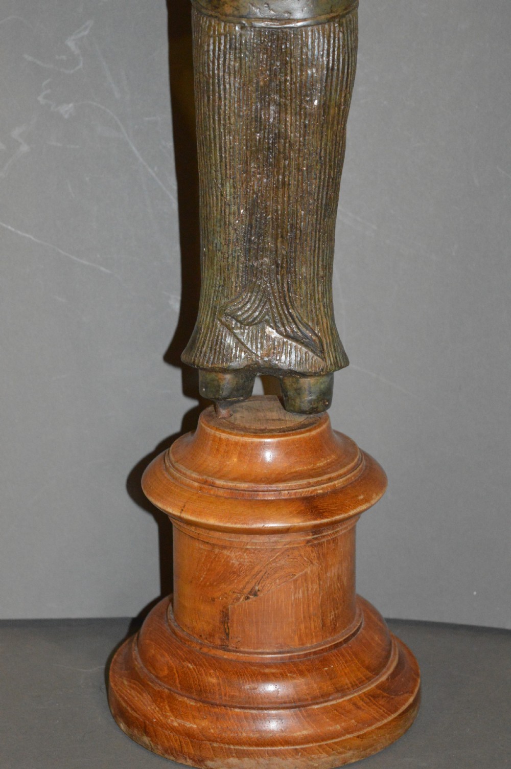 A standing patinated bronze figure of a Buddhist deity mounted on a turned wooden socle base. View III