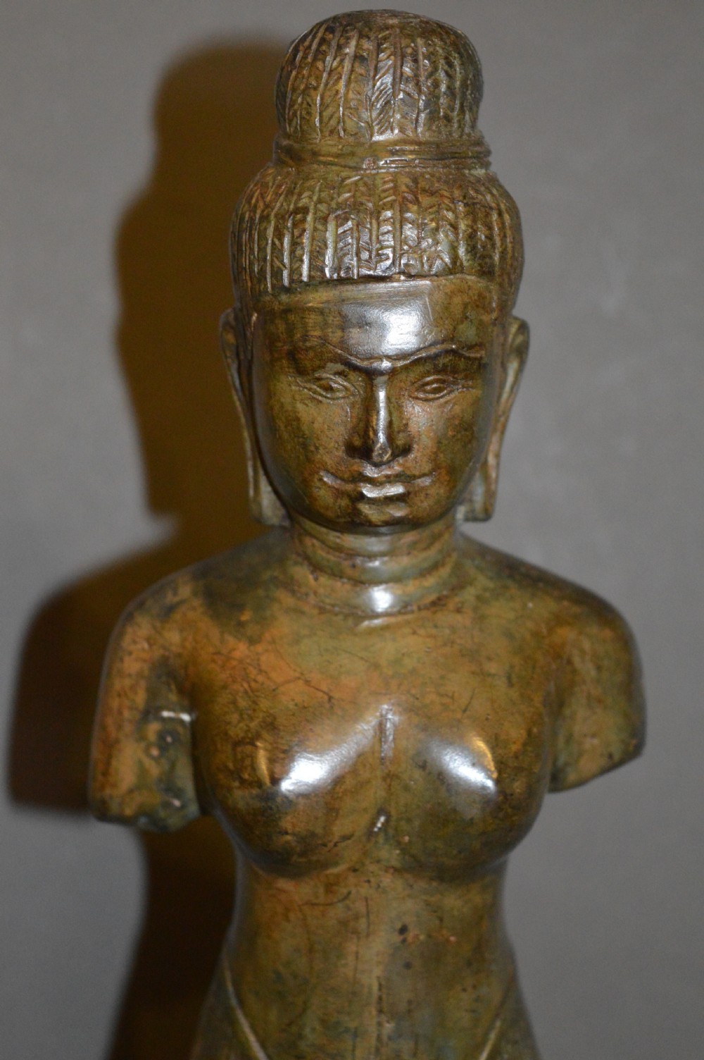 A standing patinated bronze figure of a Buddhist deity mounted on a turned wooden socle base. View IV