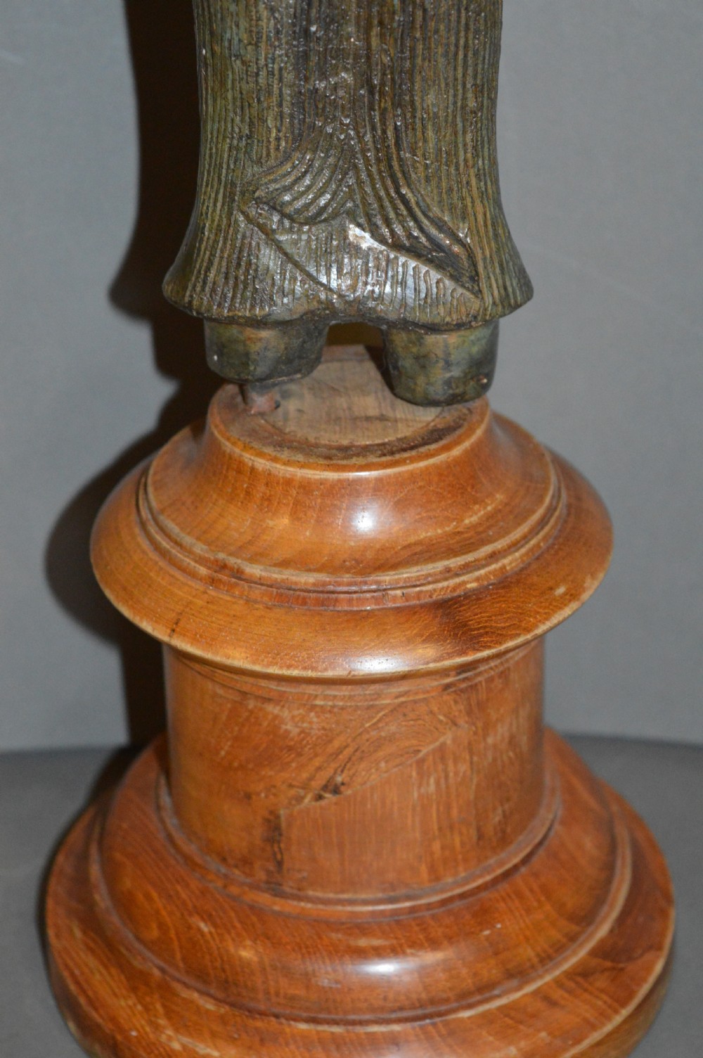 A standing patinated bronze figure of a Buddhist deity mounted on a turned wooden socle base. View VII