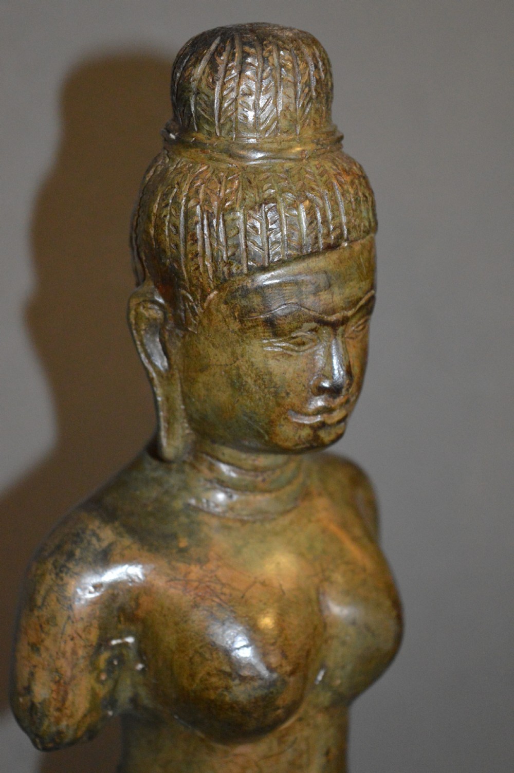 A standing patinated bronze figure of a Buddhist deity mounted on a turned wooden socle base. View VIII