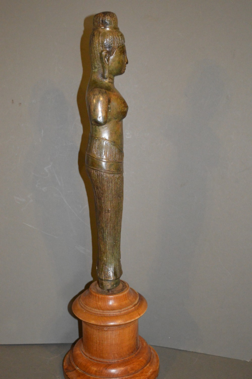 A standing patinated bronze figure of a Buddhist deity mounted on a turned wooden socle base. View IX