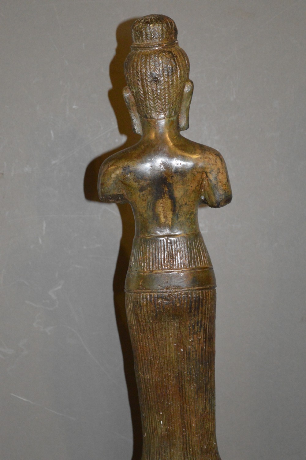 A standing patinated bronze figure of a Buddhist deity mounted on a turned wooden socle base. View XI