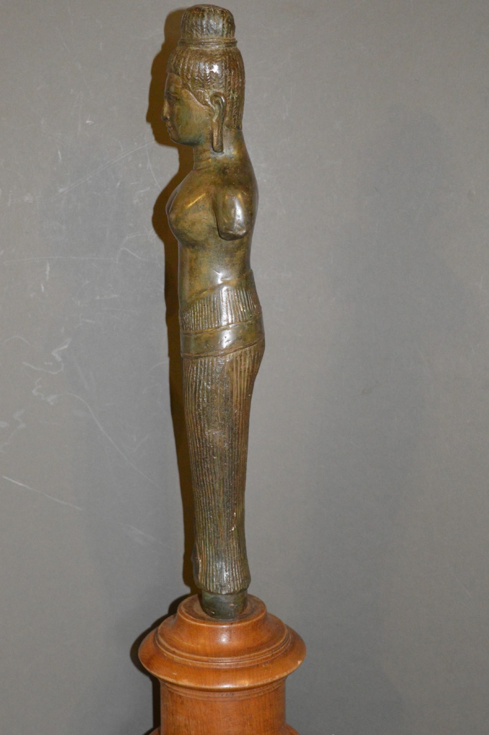 A standing patinated bronze figure of a Buddhist deity mounted on a turned wooden socle base. View XII