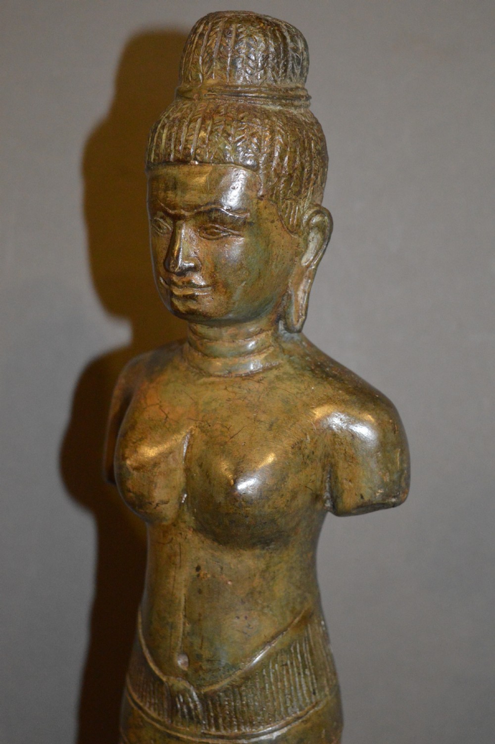 A standing patinated bronze figure of a Buddhist deity mounted on a turned wooden socle base. View XV