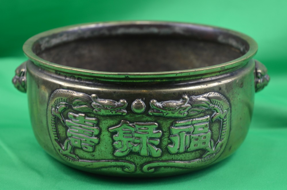 A late 19th-century Chinese cast bronze incense censer featuring raised relief Chinese character panels and side handles formed as lion masks.
