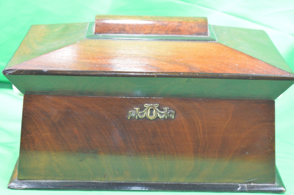 A Regency mahogany tea caddy featuring a tapered sarcophagus shape, stepped hinged lid, and central brass keyhole escutcheon.