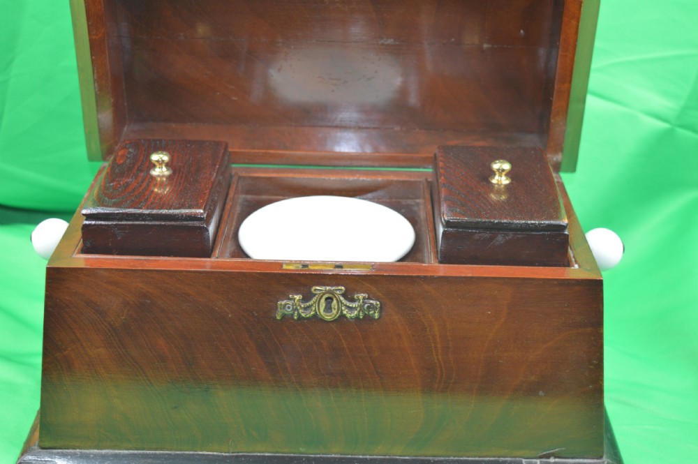 A Regency mahogany tea caddy featuring a tapered sarcophagus shape, stepped hinged lid, and central brass keyhole escutcheon. View III
