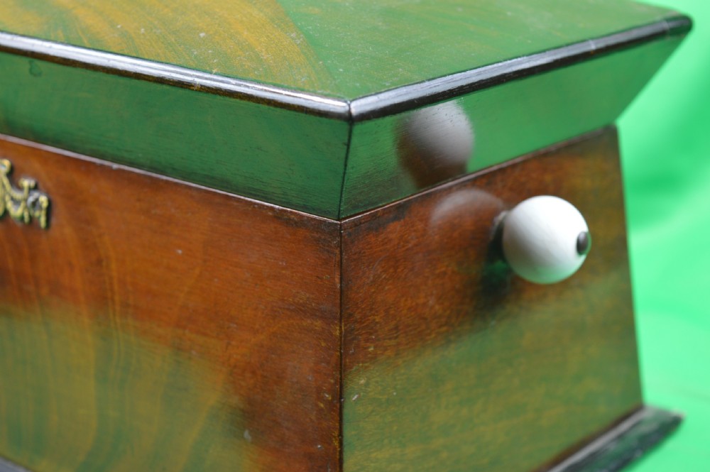 A Regency mahogany tea caddy featuring a tapered sarcophagus shape, stepped hinged lid, and central brass keyhole escutcheon. View VIII