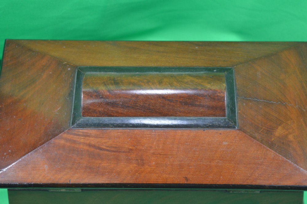 A Regency mahogany tea caddy featuring a tapered sarcophagus shape, stepped hinged lid, and central brass keyhole escutcheon. View XII