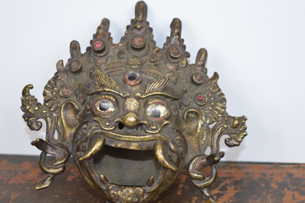 A late 19th-century Tibetan cast bronze incense burner depicting the wrathful deity Mahakala with open mouth and glass inlays.