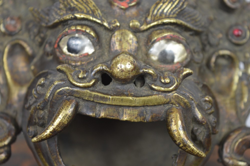 A late 19th-century Tibetan cast bronze incense burner depicting the wrathful deity Mahakala with open mouth and glass inlays. View II