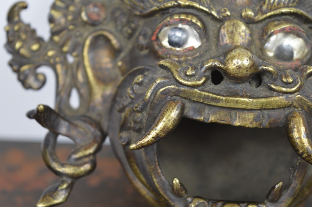 A late 19th-century Tibetan cast bronze incense burner depicting the wrathful deity Mahakala with open mouth and glass inlays. View V
