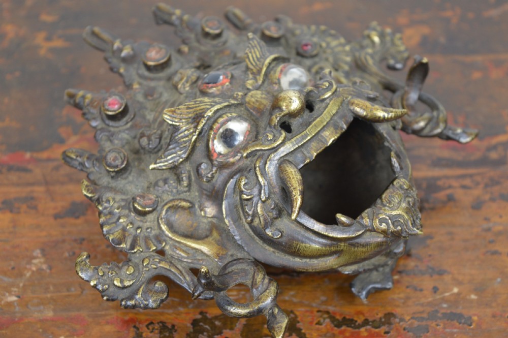A late 19th-century Tibetan cast bronze incense burner depicting the wrathful deity Mahakala with open mouth and glass inlays. View X