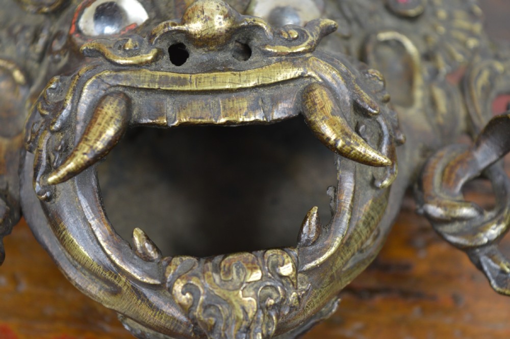 A late 19th-century Tibetan cast bronze incense burner depicting the wrathful deity Mahakala with open mouth and glass inlays. View XI