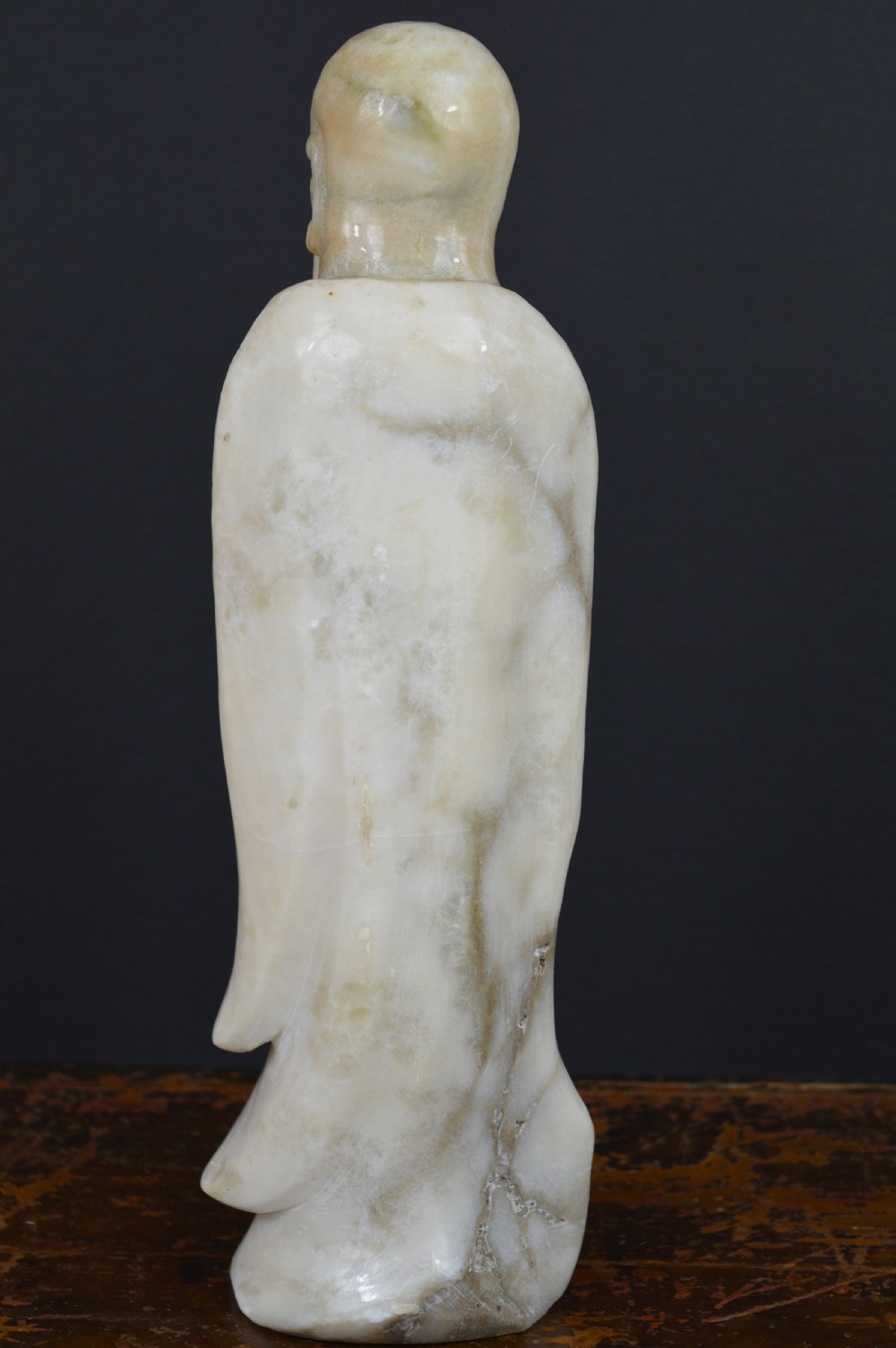 A cream-coloured carved hardstone sculpture depicting a standing bearded Chinese sage in long flowing robes holding a fish on a cord. View III