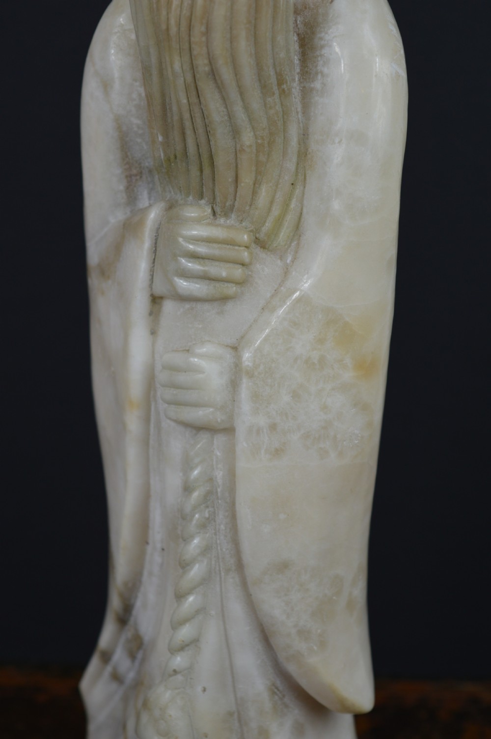 A cream-coloured carved hardstone sculpture depicting a standing bearded Chinese sage in long flowing robes holding a fish on a cord. View VI