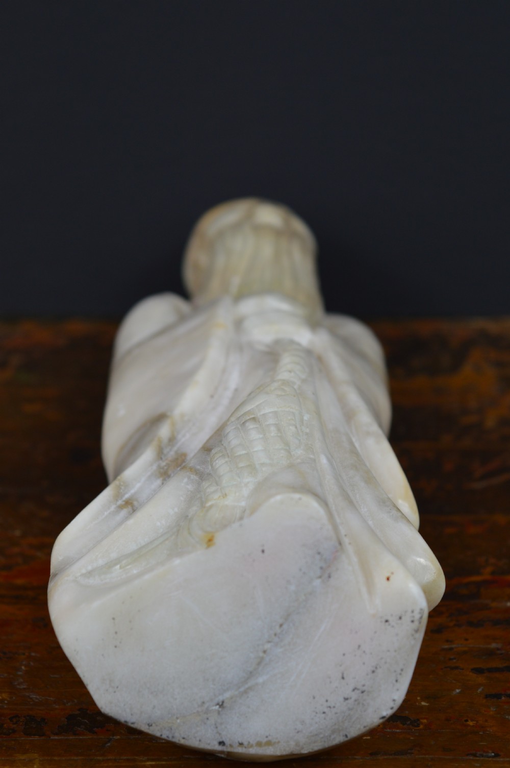 A cream-coloured carved hardstone sculpture depicting a standing bearded Chinese sage in long flowing robes holding a fish on a cord. View VIII